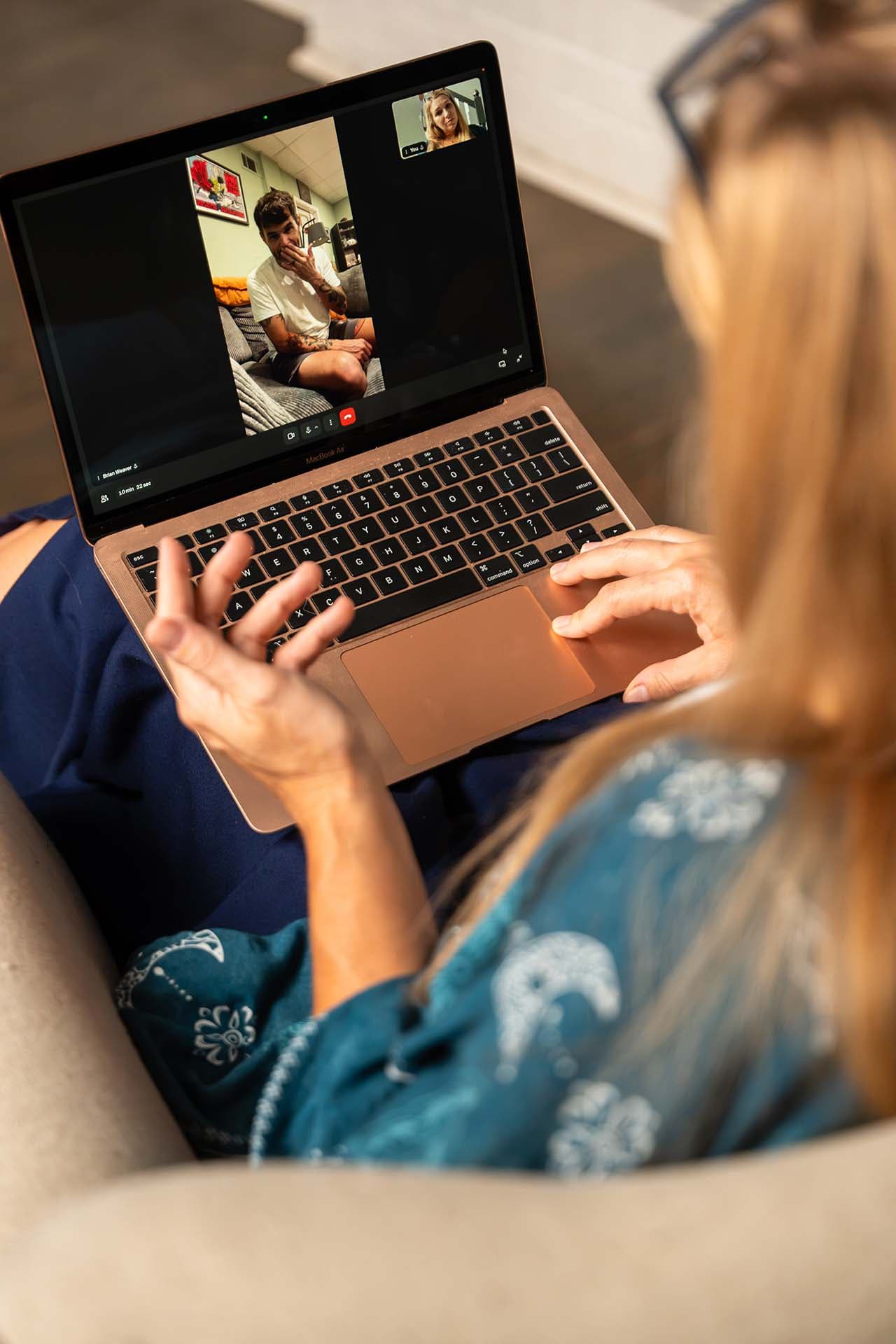 over the shoulder view of Kate on a telehealth psychiatry meeting